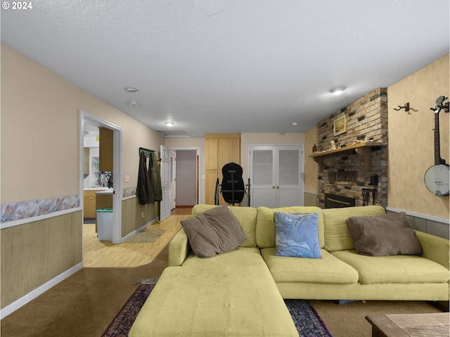 living room featuring a textured ceiling, a brick fireplace, and wooden walls