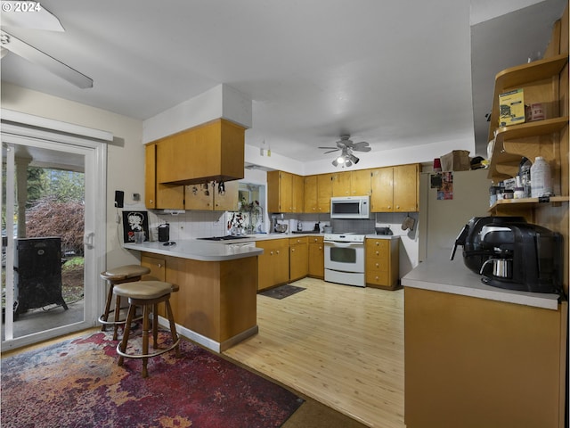 kitchen with white appliances, light hardwood / wood-style flooring, decorative backsplash, ceiling fan, and kitchen peninsula