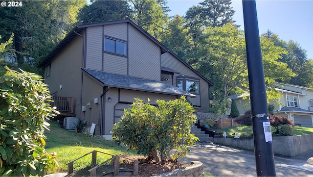 view of property exterior with a garage, cooling unit, and a lawn