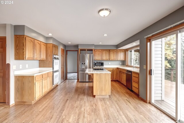 kitchen with sink, stainless steel appliances, light hardwood / wood-style flooring, and a kitchen island