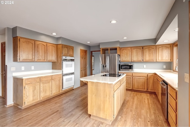 kitchen with sink, stainless steel appliances, light wood-type flooring, and a center island