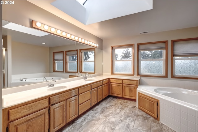 bathroom with vanity, tiled tub, and a skylight