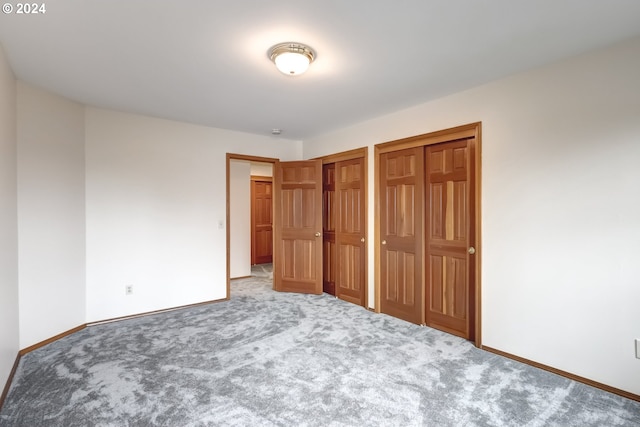 unfurnished bedroom with multiple closets and carpet floors