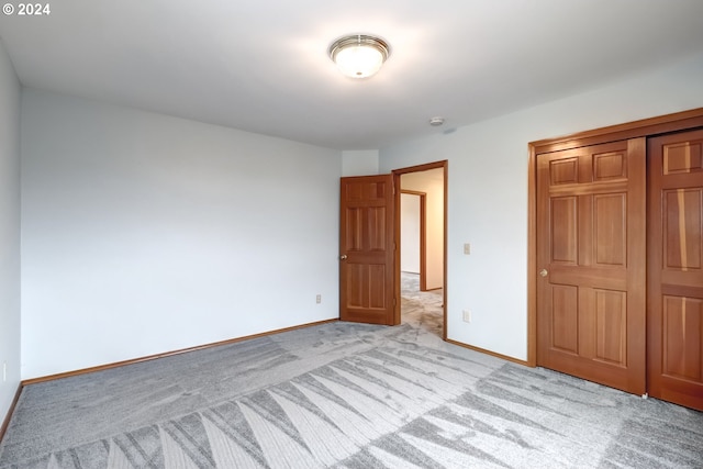 unfurnished bedroom featuring a closet and light carpet