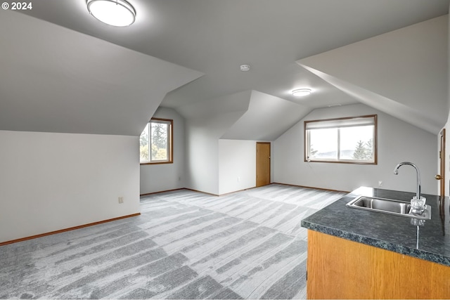 bonus room with vaulted ceiling, light carpet, and sink