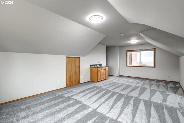 additional living space featuring sink, light carpet, and lofted ceiling