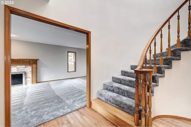 stairway featuring a tile fireplace and hardwood / wood-style flooring