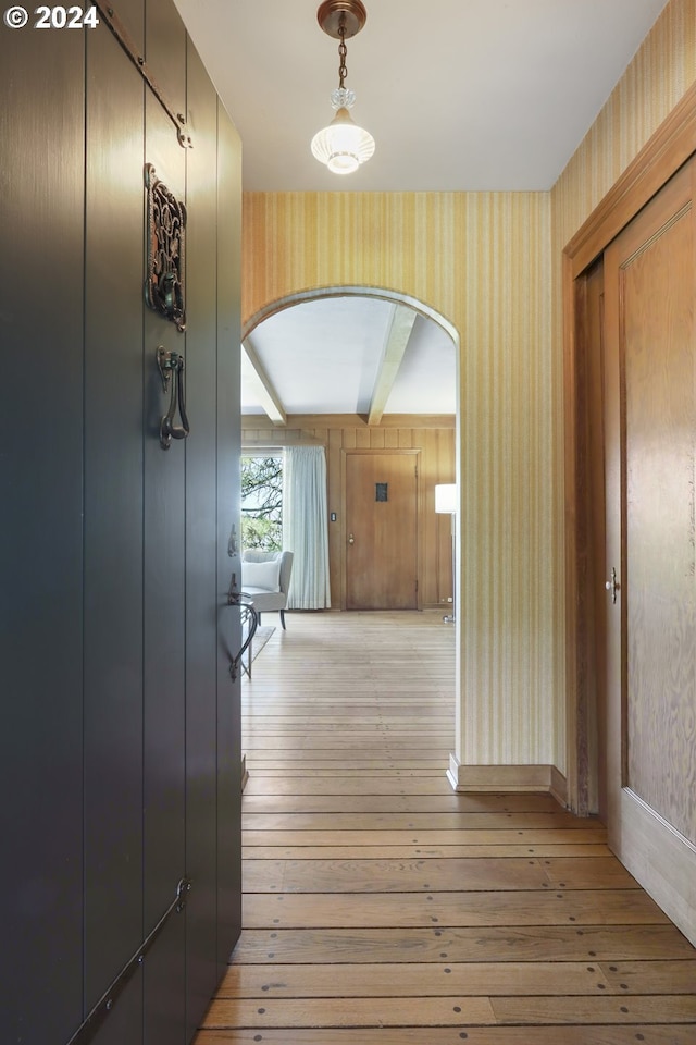 corridor featuring light hardwood / wood-style flooring and wood walls