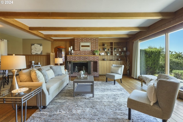 living room with a fireplace, hardwood / wood-style floors, wooden walls, and beamed ceiling