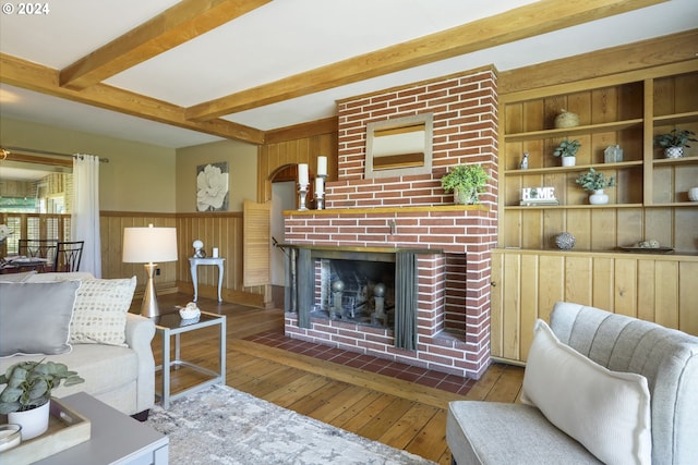 living room featuring dark hardwood / wood-style floors, beam ceiling, a fireplace, and wooden walls