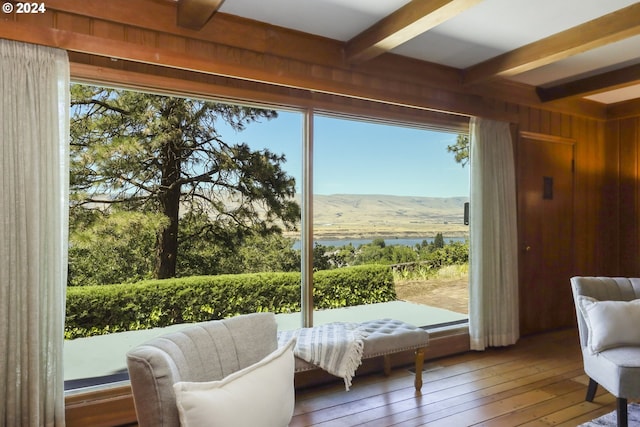 doorway with hardwood / wood-style floors, a mountain view, beam ceiling, and wooden walls