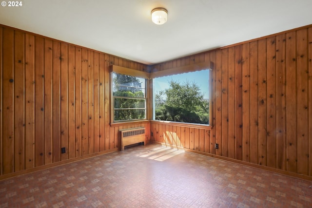 empty room featuring wooden walls and radiator