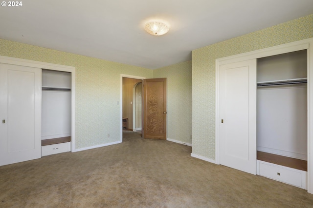 unfurnished bedroom with multiple closets and carpet floors