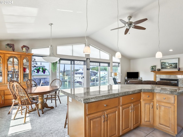 kitchen featuring vaulted ceiling, pendant lighting, a kitchen bar, ceiling fan, and light colored carpet