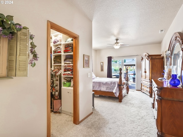 bedroom featuring ceiling fan, light colored carpet, access to exterior, and a textured ceiling