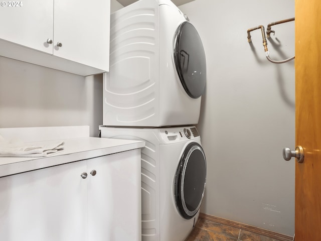 laundry area with cabinets and stacked washer and clothes dryer