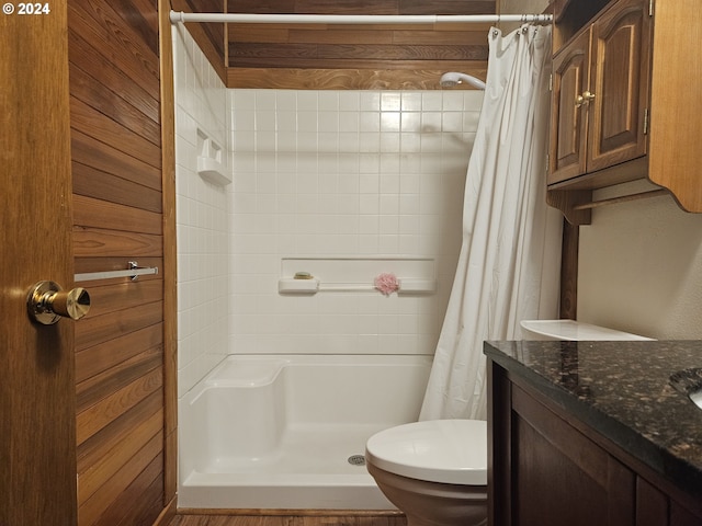 bathroom featuring curtained shower, wooden walls, toilet, and vanity