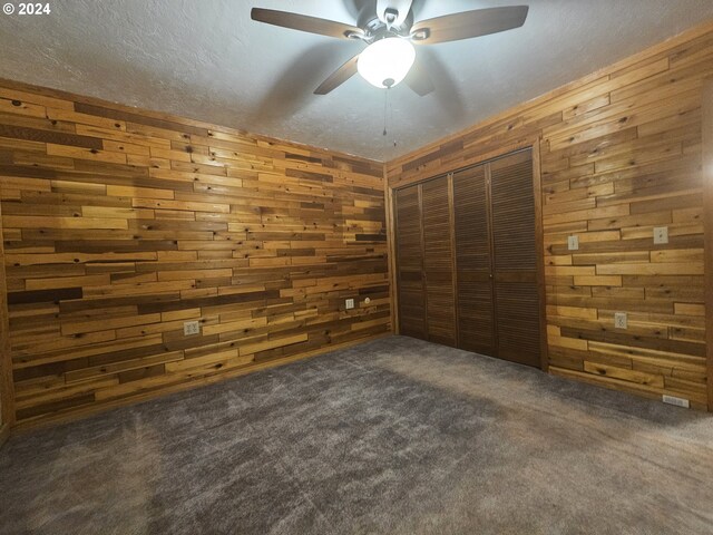 interior space featuring wood walls, a closet, and dark carpet