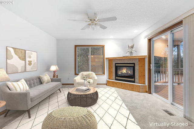 living room featuring ceiling fan, a fireplace, and a textured ceiling