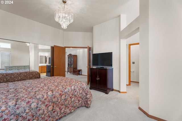 bedroom with a chandelier, light colored carpet, and ensuite bath