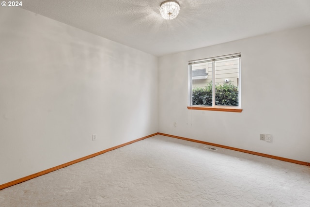 carpeted empty room featuring a textured ceiling