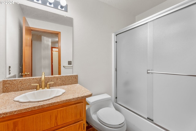 full bathroom with toilet, vanity, a textured ceiling, and shower / bath combination with glass door