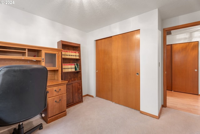 carpeted office featuring a textured ceiling