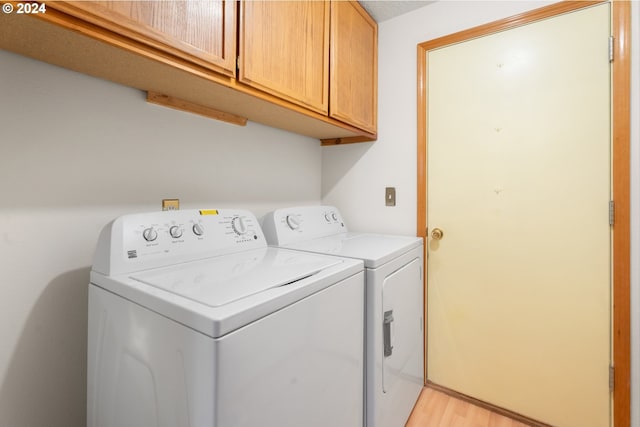 laundry room featuring cabinets, washing machine and clothes dryer, and light hardwood / wood-style floors