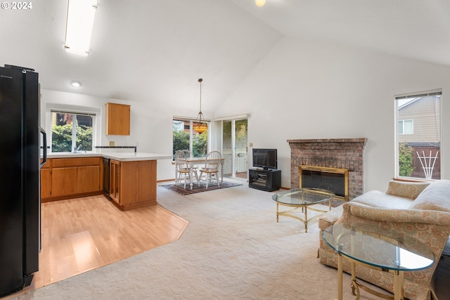 living room with a brick fireplace, high vaulted ceiling, light carpet, and sink