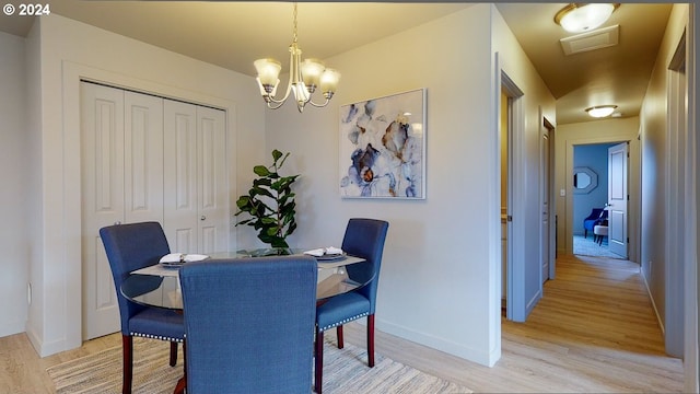 dining area with a notable chandelier and light hardwood / wood-style floors