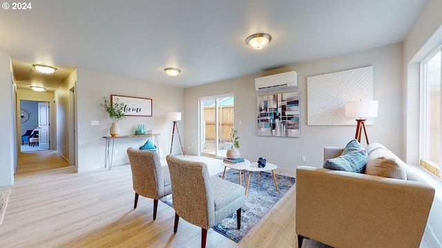 living area with an AC wall unit and light hardwood / wood-style floors