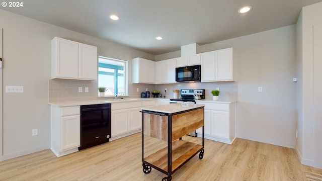 kitchen featuring sink, backsplash, light hardwood / wood-style floors, black appliances, and white cabinetry