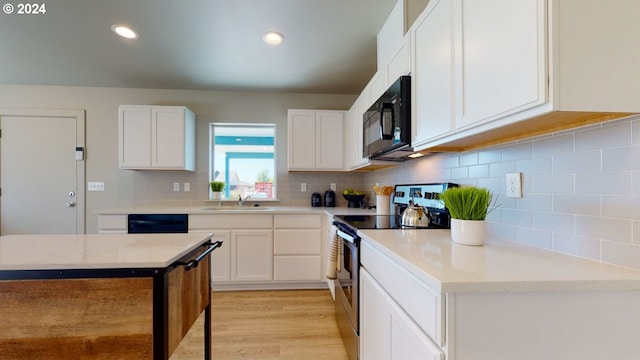 kitchen featuring sink, white cabinets, light hardwood / wood-style flooring, backsplash, and black appliances