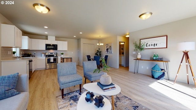 living room with a notable chandelier, light hardwood / wood-style flooring, and sink