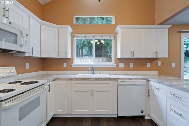 kitchen featuring light stone countertops, sink, dark hardwood / wood-style flooring, white appliances, and white cabinets