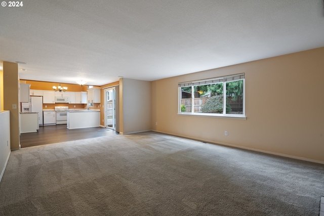 unfurnished living room with carpet, a chandelier, and a textured ceiling