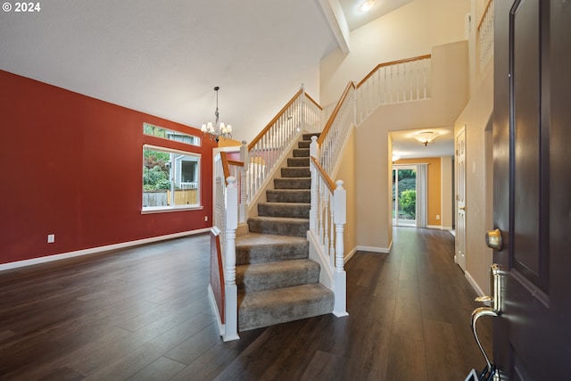 entryway featuring dark wood-type flooring, a towering ceiling, and a healthy amount of sunlight