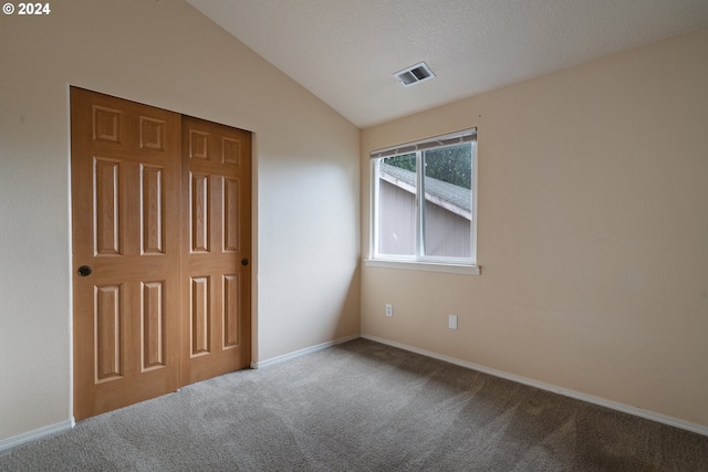 carpeted spare room with lofted ceiling and a textured ceiling