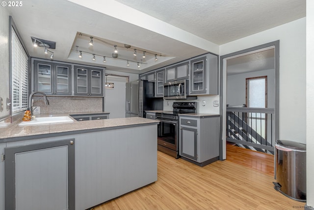 1504 SW 24th St, Troutdale, OR 97060 - kitchen with appliances with stainless steel finishes, a sink, gray cabinetry, light wood-type flooring, and a peninsula