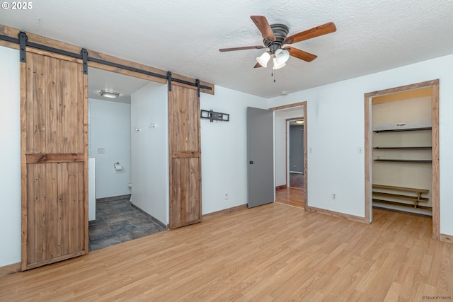 1504 SW 24th St, Troutdale, OR 97060 - unfurnished bedroom featuring a barn door, wood finished floors, a spacious closet, a textured ceiling, and baseboards