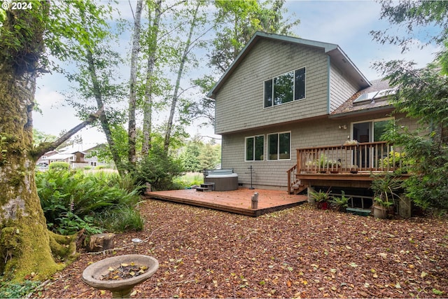 rear view of house featuring a hot tub and a wooden deck