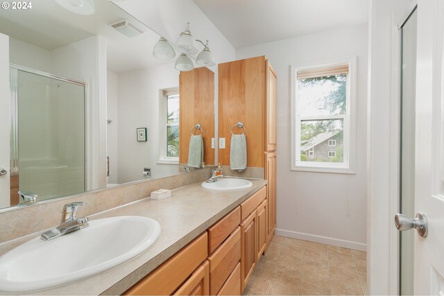 bathroom featuring a shower with door, vanity, plenty of natural light, and tile patterned floors