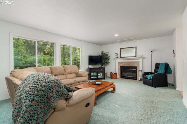 living room featuring a tiled fireplace, rail lighting, and carpet floors