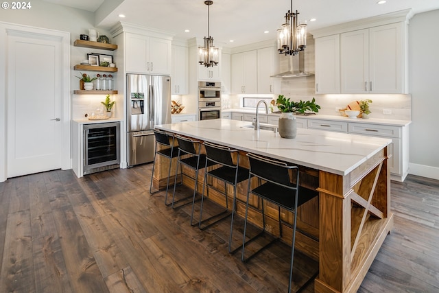 kitchen featuring stainless steel appliances, a kitchen island with sink, white cabinets, and beverage cooler