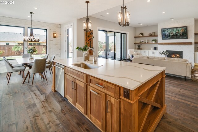 kitchen featuring dishwasher, sink, a kitchen island with sink, and an inviting chandelier