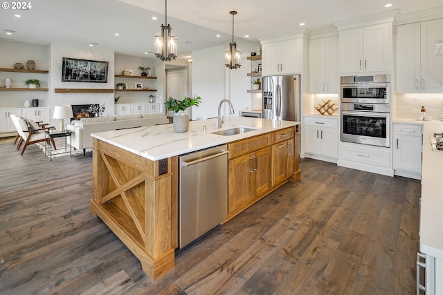 kitchen featuring white cabinetry, stainless steel appliances, an island with sink, and light stone counters