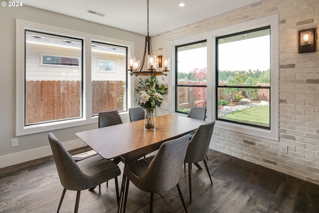 dining room with brick wall, dark hardwood / wood-style floors, and a chandelier