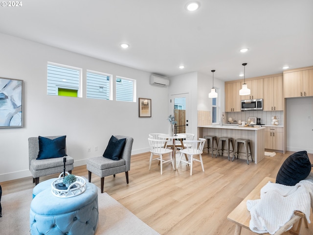 living room with light hardwood / wood-style floors, an AC wall unit, and sink