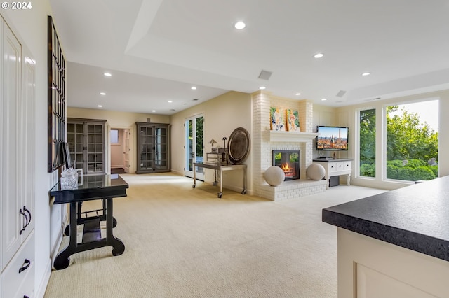 living area featuring brick wall, light colored carpet, and a brick fireplace