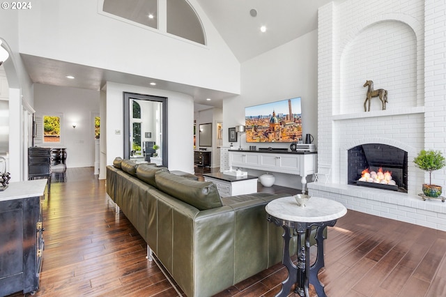 living room with a fireplace, brick wall, high vaulted ceiling, and dark hardwood / wood-style flooring